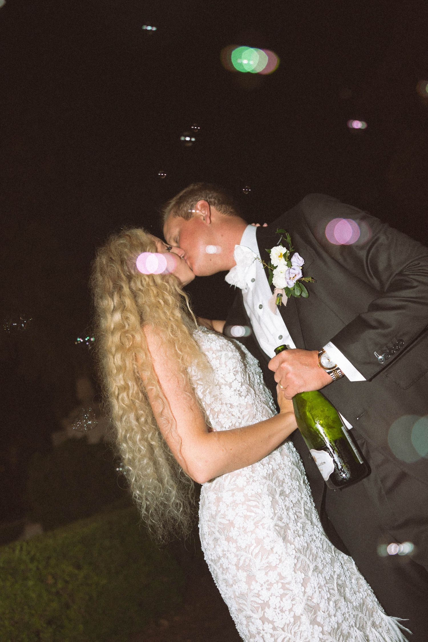 A couple in formal wedding attire share a romantic dance together at a dimly lit evening reception.