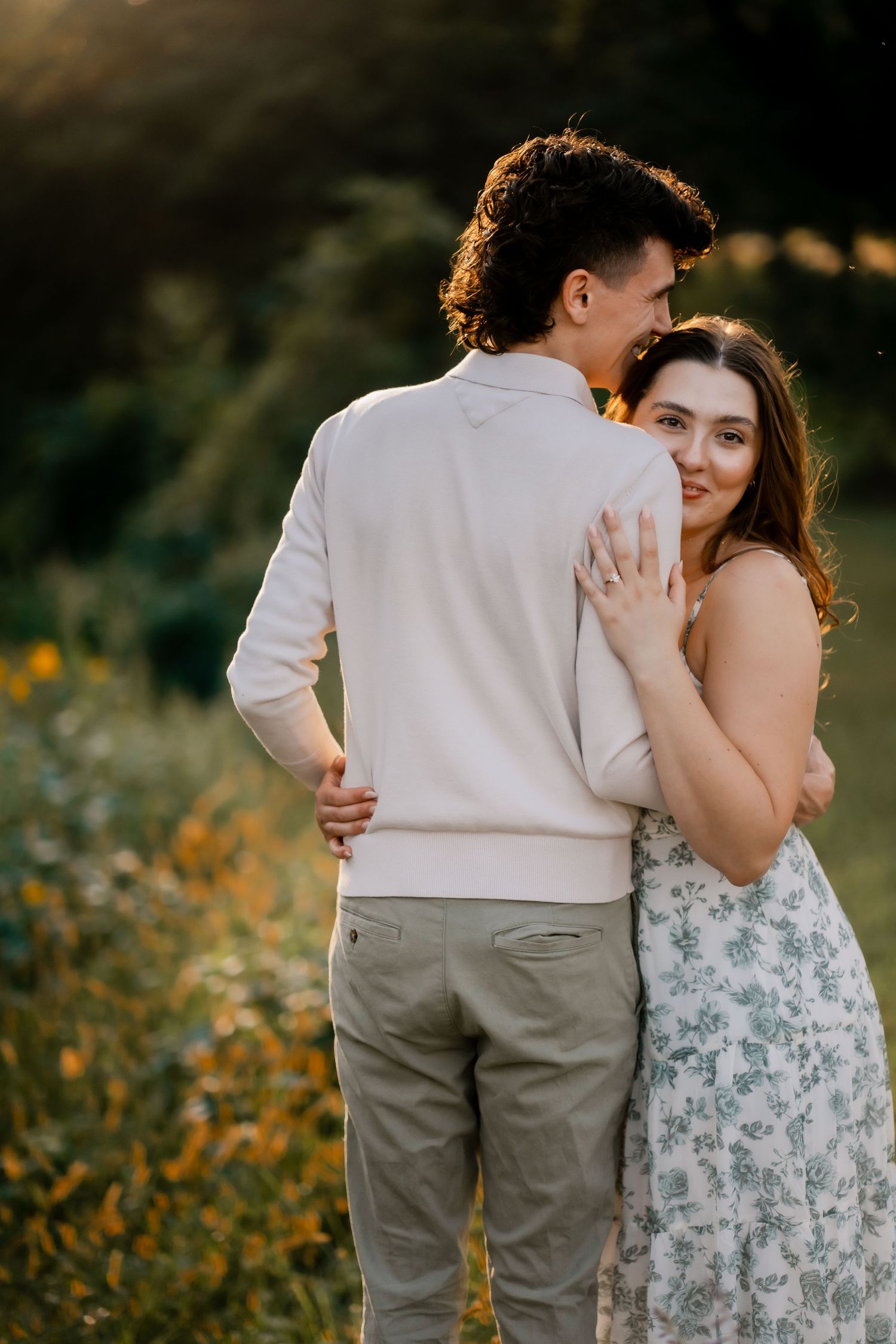 Romantic couple embracing in a wildflower meadow during golden hour.