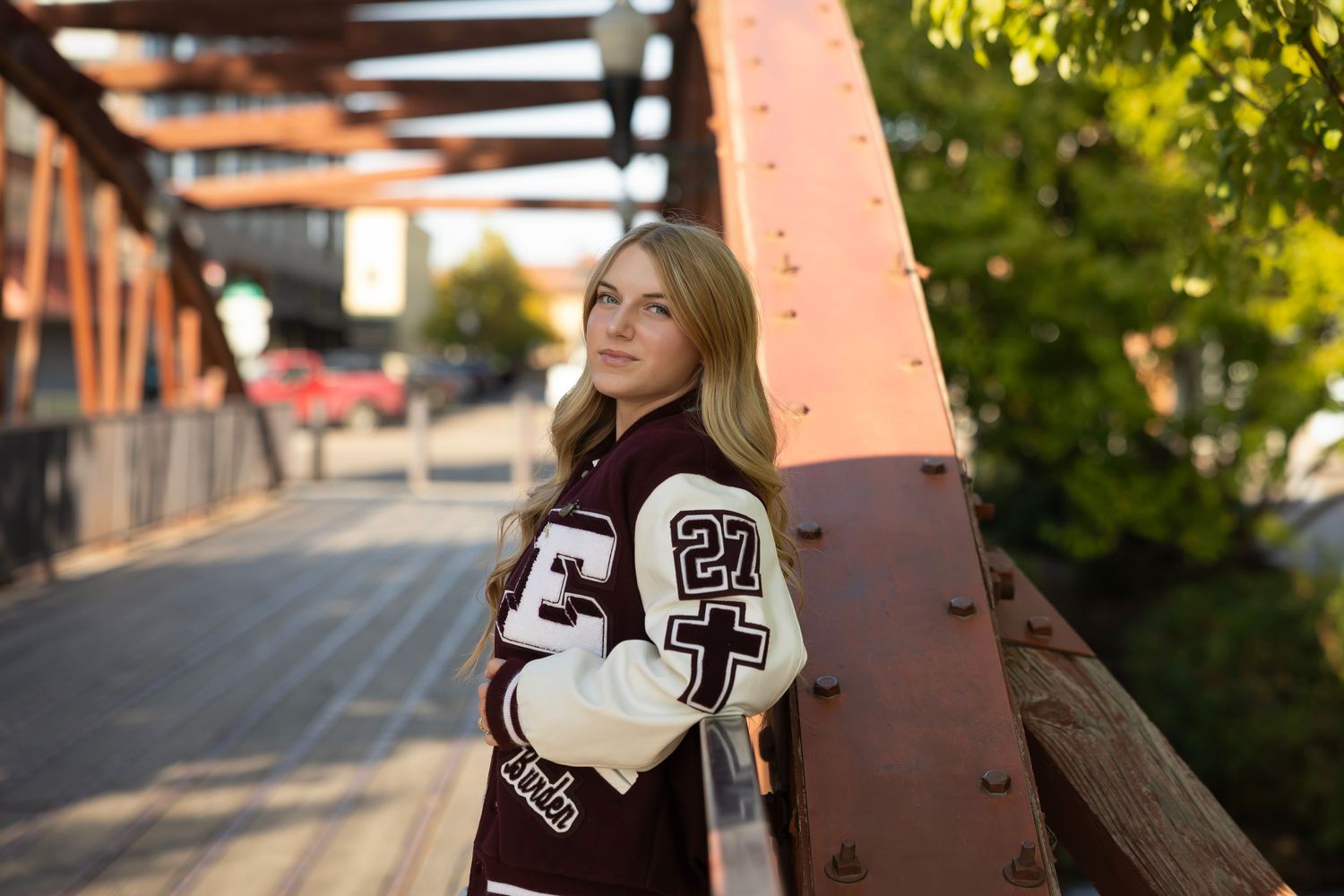 senior girl on bridge wearing letterman's jacket
