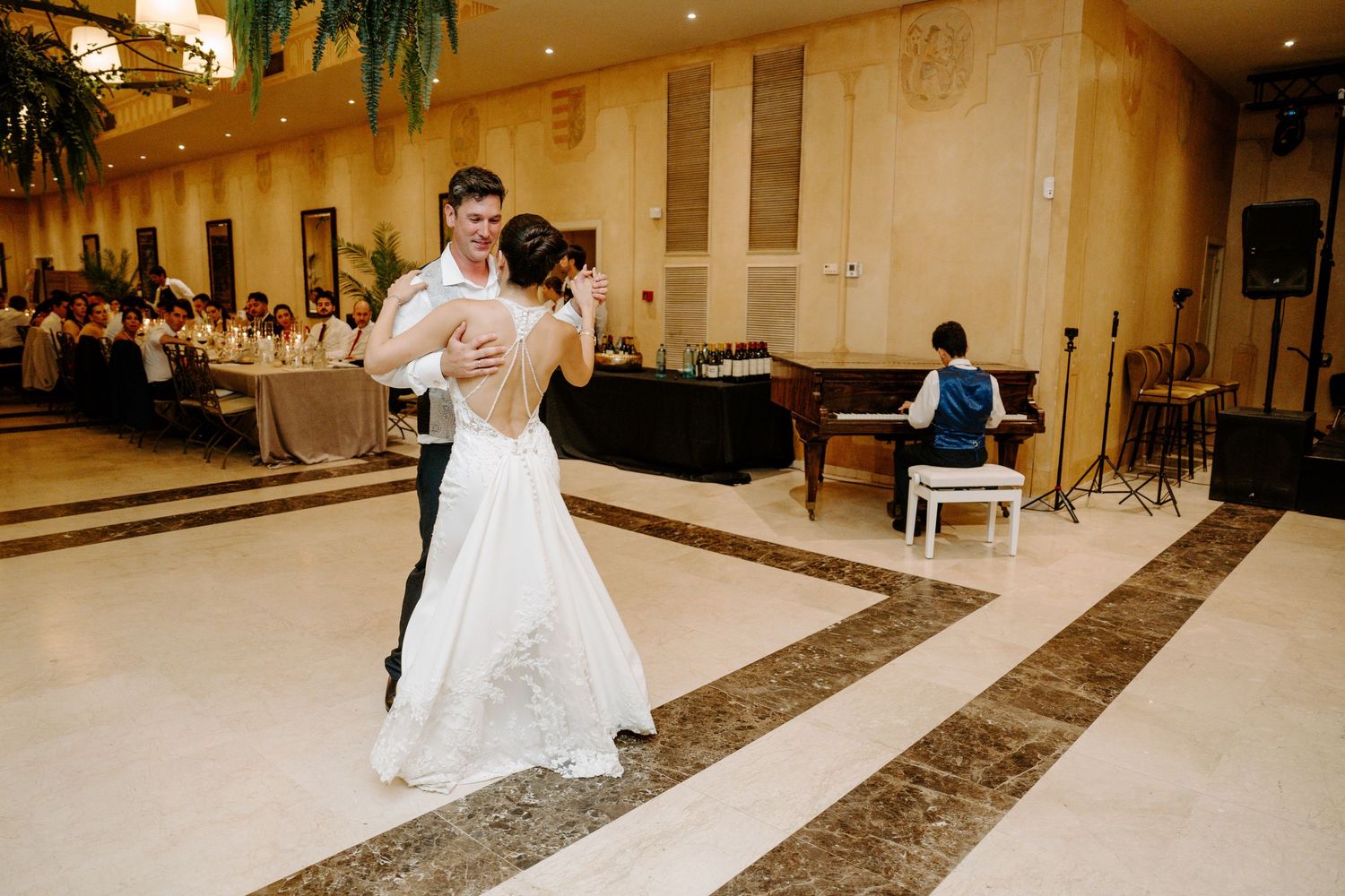 Bride and groom share romantic first dance on marble ballroom floor at elegant wedding reception.