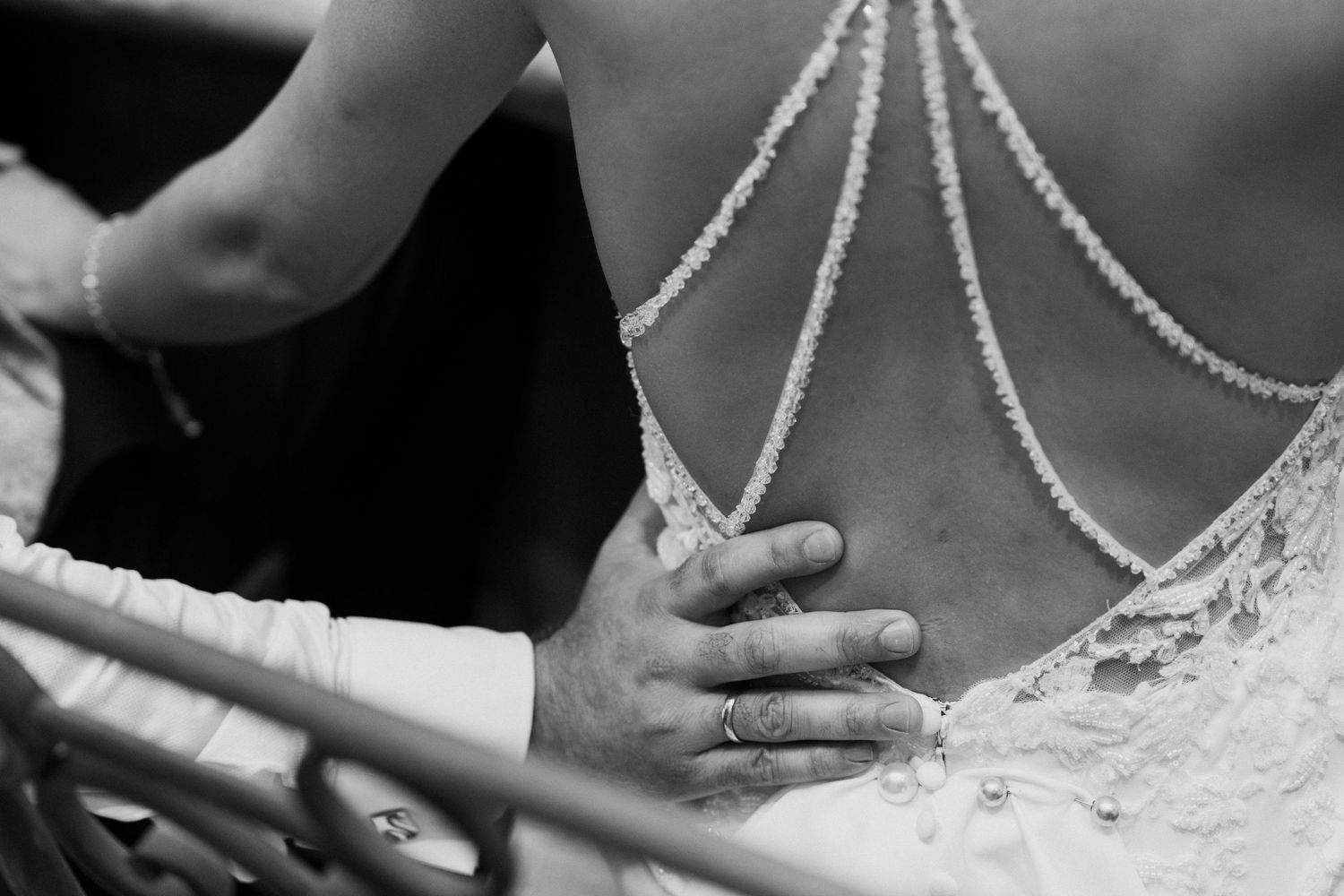Black and white close-up of intricate pearl and lace detail on back of bridal wedding gown.