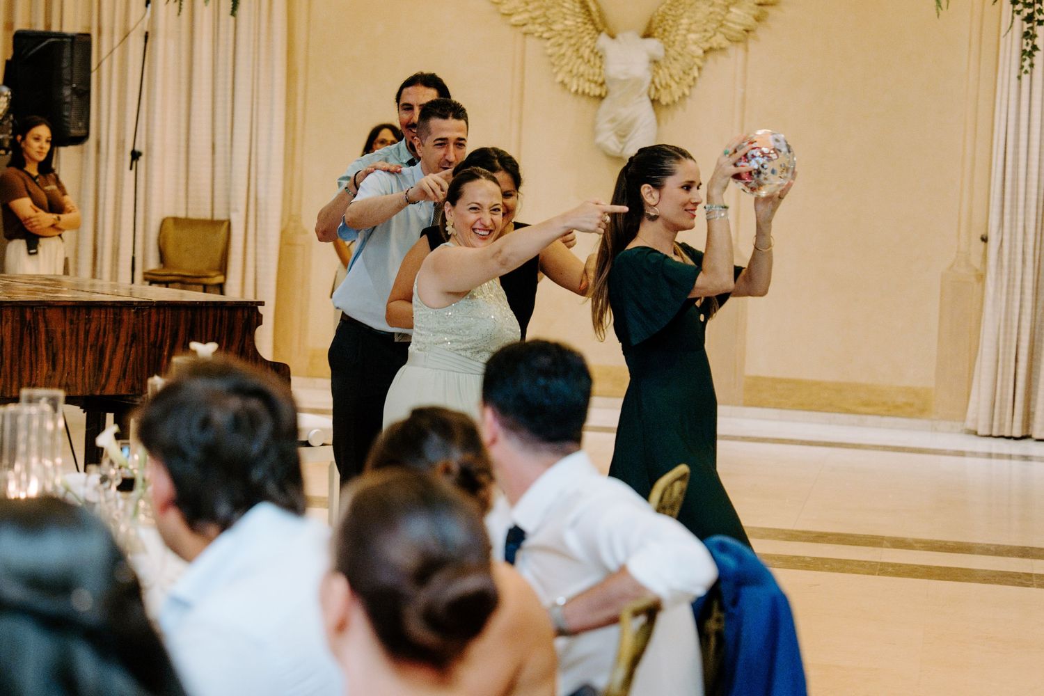 Wedding guests joyfully celebrating and dancing together in a grand ballroom during the wedding reception.