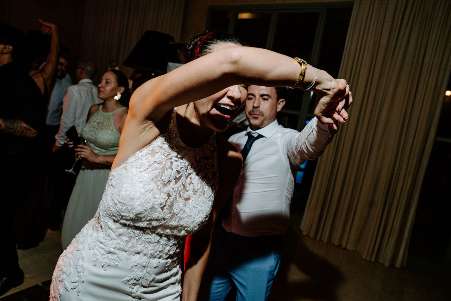 Bride and groom dancing energetically at lively wedding reception party.