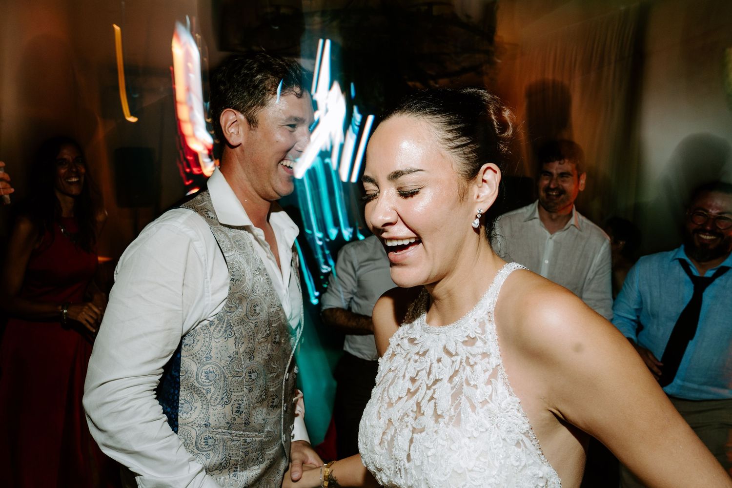 Bride and groom laughing and dancing together at their wedding reception party.