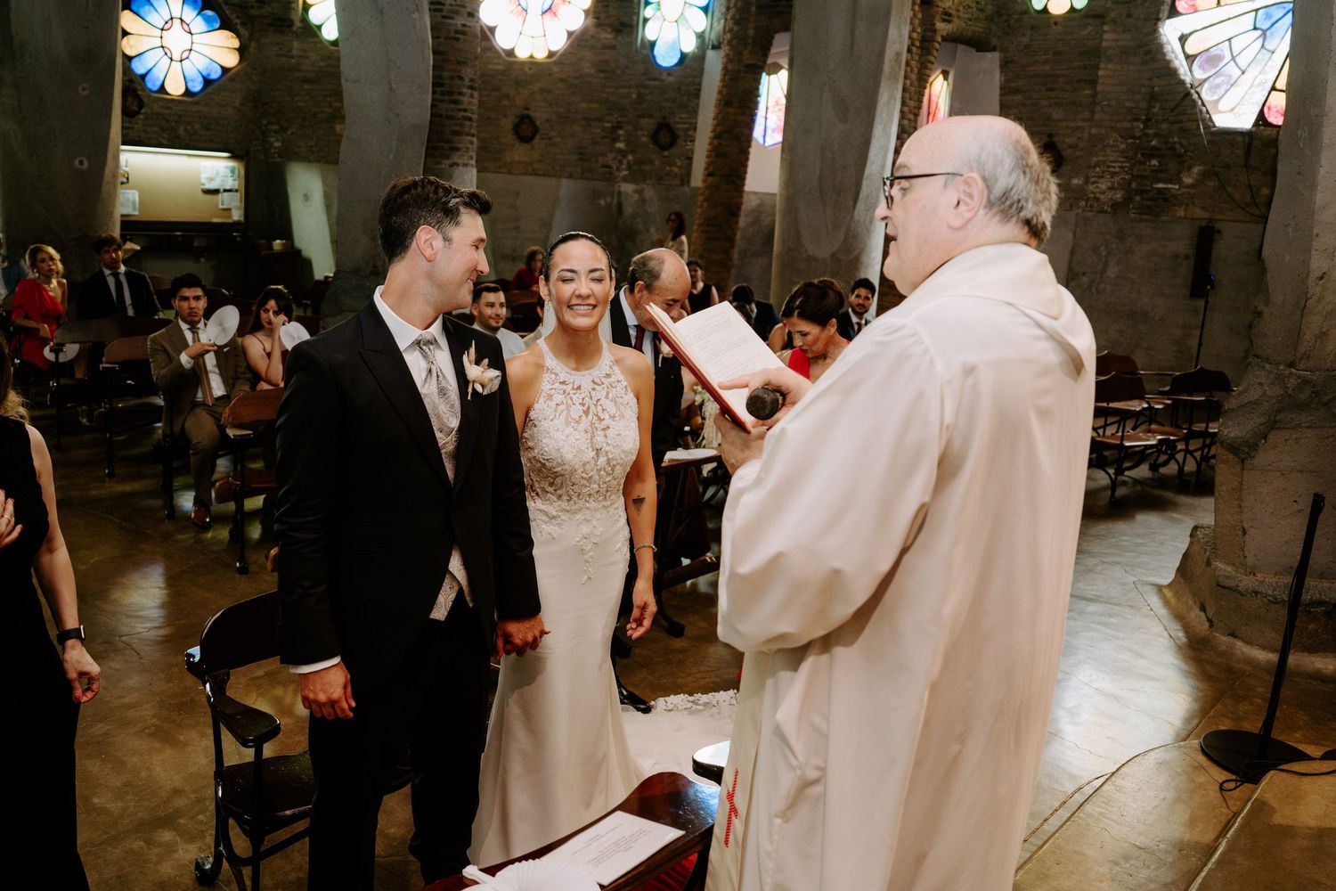 Bride and groom exchange vows with officiant inside a historic stone church wedding ceremony.
