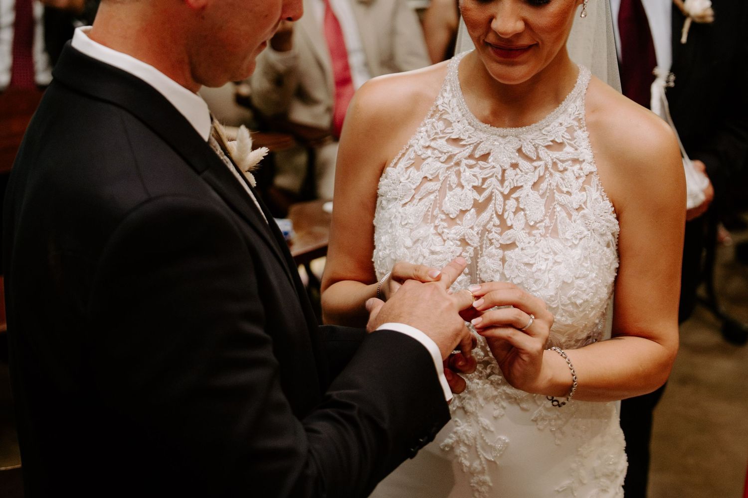 Groom placing a wedding ring on the brides finger during the ring exchange ceremony at the altar.