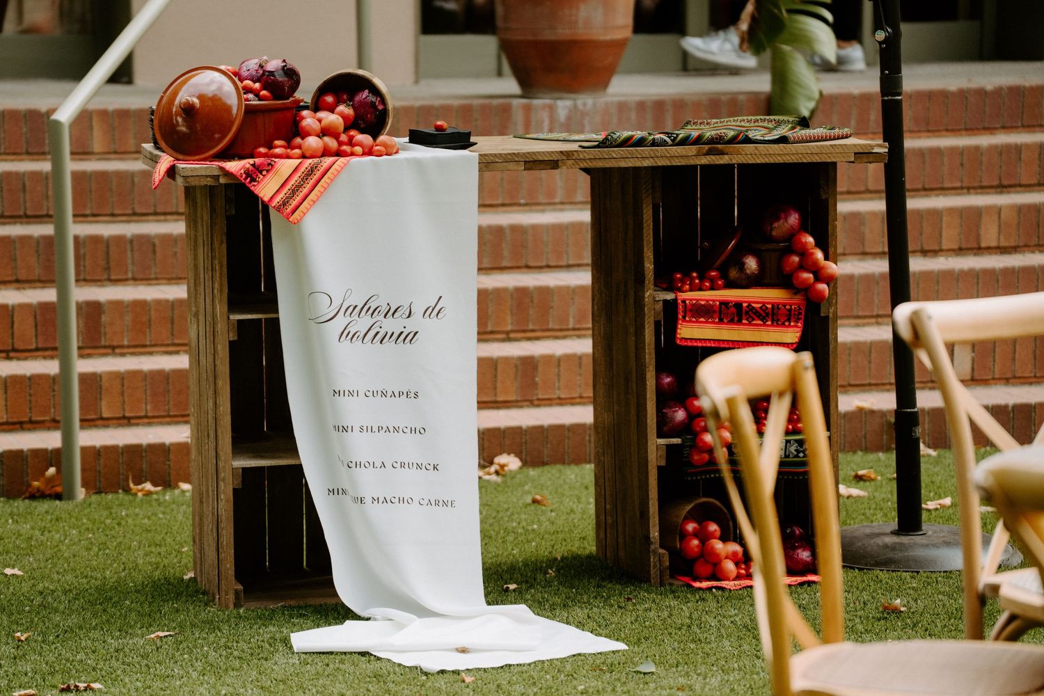 Elegant outdoor wedding menu sign displayed beside wooden crates filled with colorful fresh fruits.