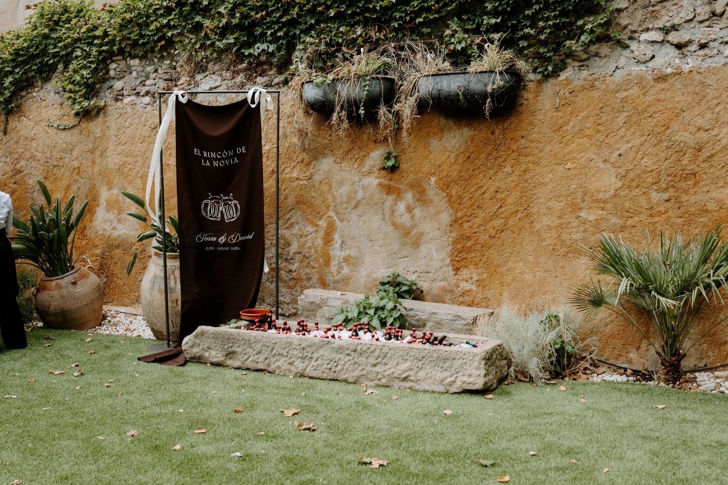 Rustic wedding banner display against a textured orange wall in a garden ceremony space.