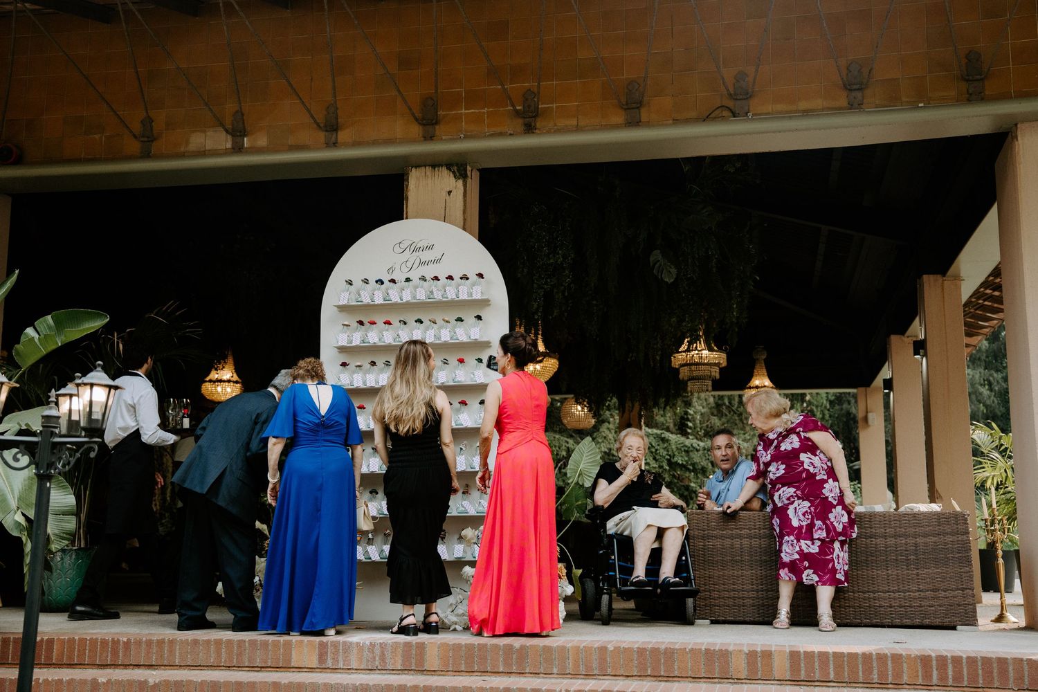 Wedding guests browsing seating chart display at outdoor venue reception area.