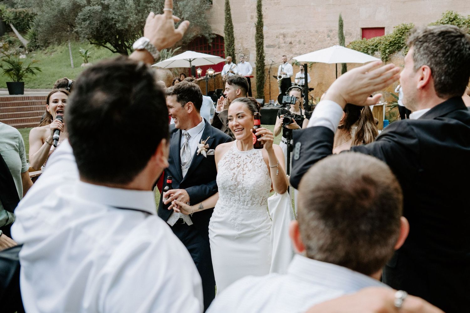 Happy bride in white gown celebrating with guests at outdoor wedding reception party.