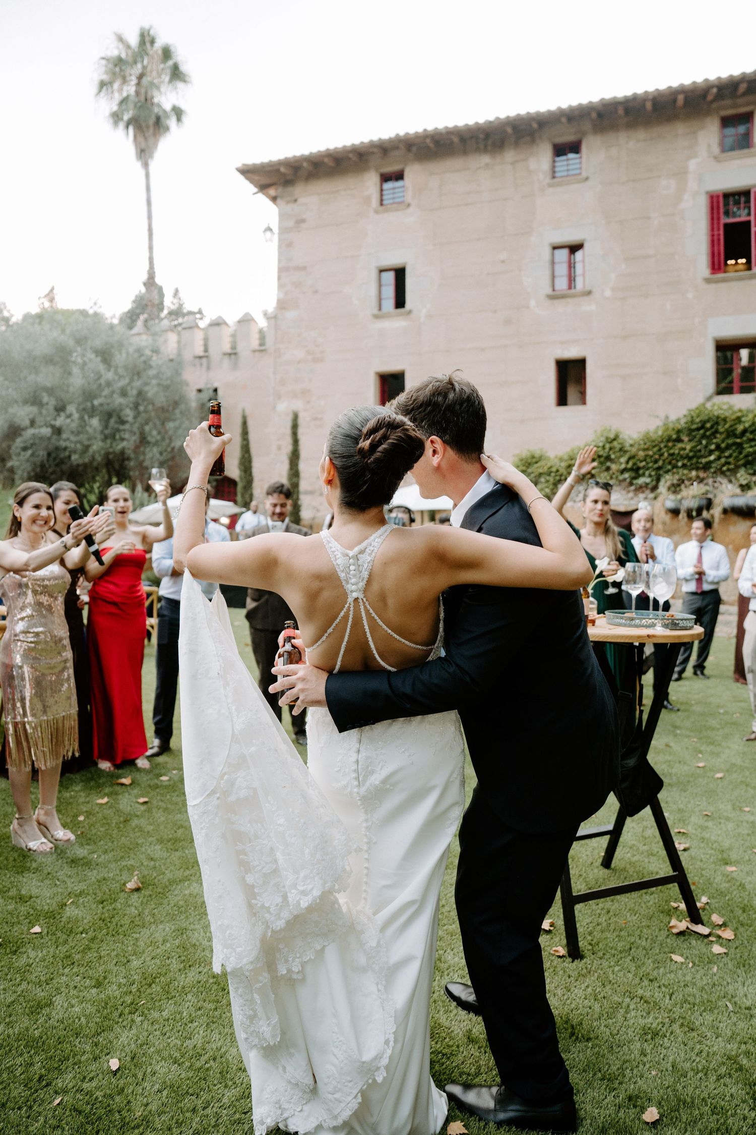 Bride and groom share first dance outdoors at elegant venue while wedding guests celebrate around them.