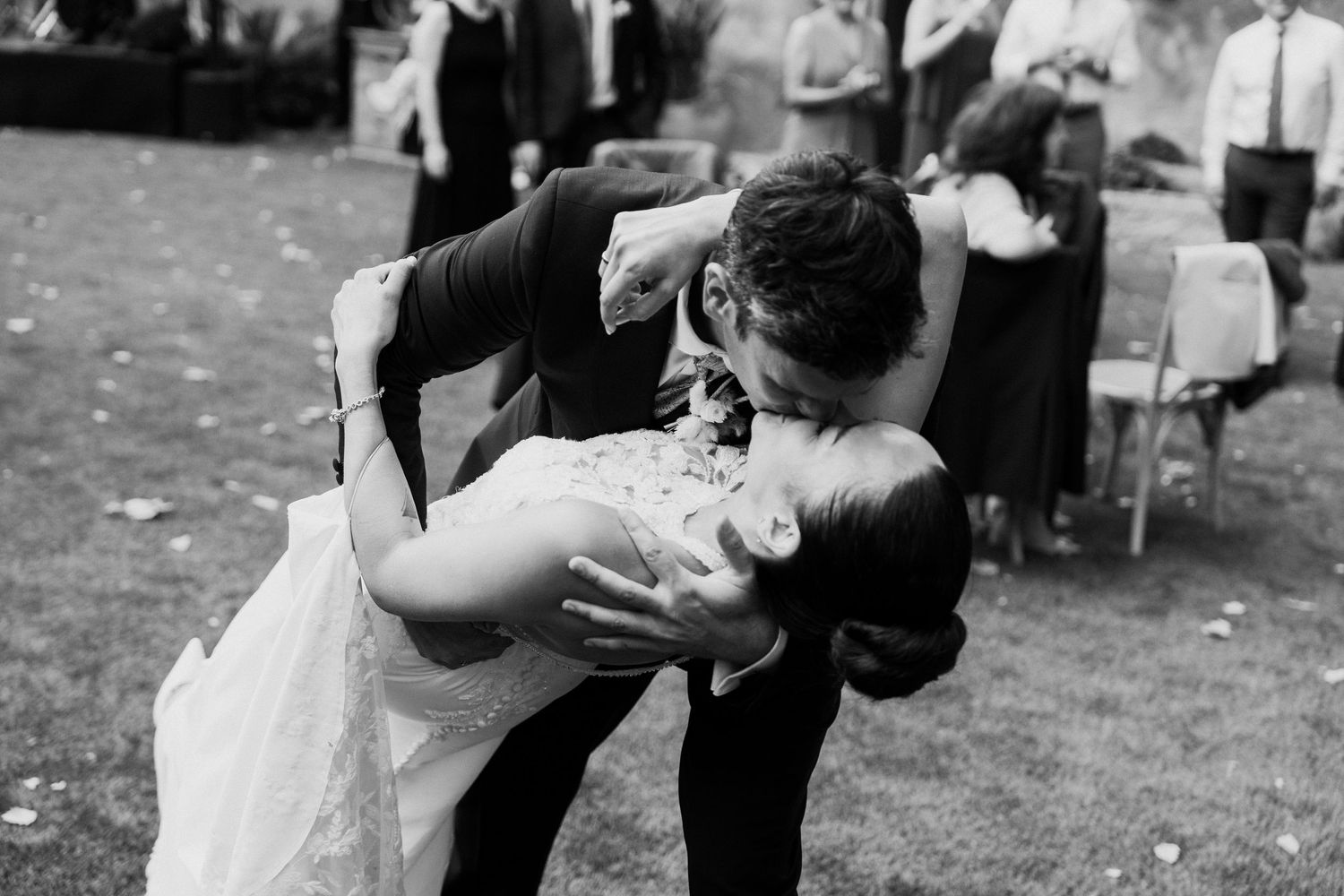 Bride and groom share a romantic dip kiss during their outdoor wedding reception dance.
