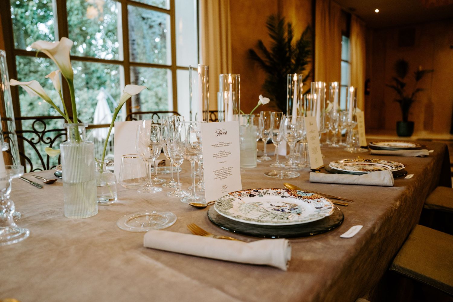 Beautifully set wedding dinner table with crystal glasses, white candles, and floral centerpieces.