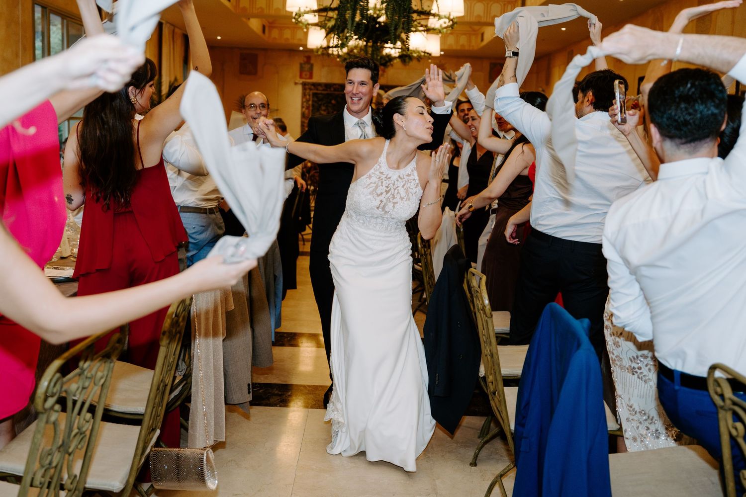 Bride and groom walk down the aisle as wedding guests wave white napkins in celebration.