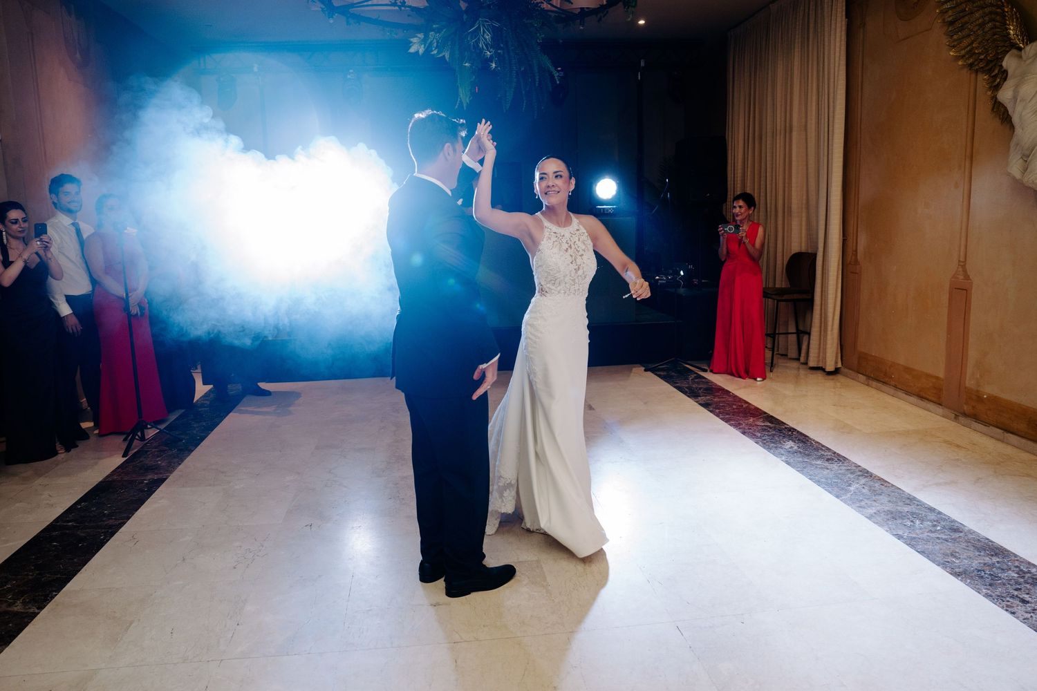 Bride and groom sharing their first dance on a white dance floor surrounded by dramatic fog effects.
