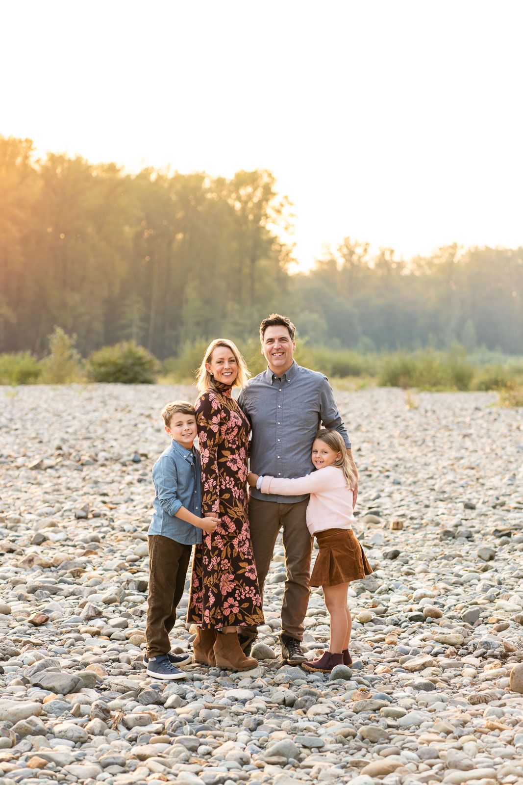 Family backlit by the golden sunshine at sunset by the Snoqualmie river.
