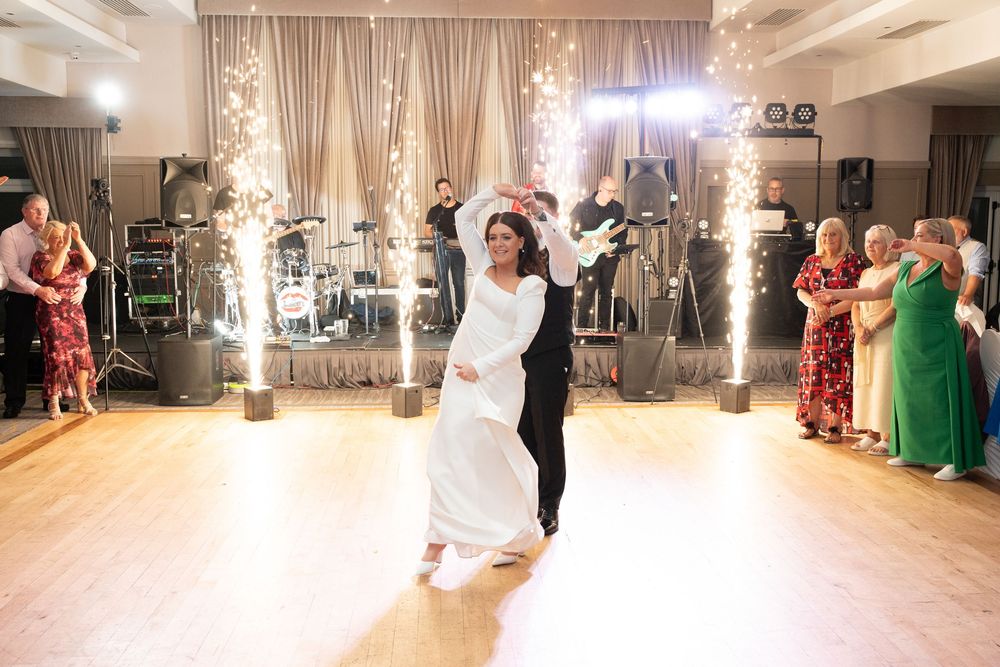 Bride and groom share first dance surrounded by sparkling fountains at elegant wedding reception.