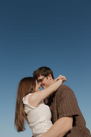 A romantic couple embraces against a blue sky background in a series of connected photos.