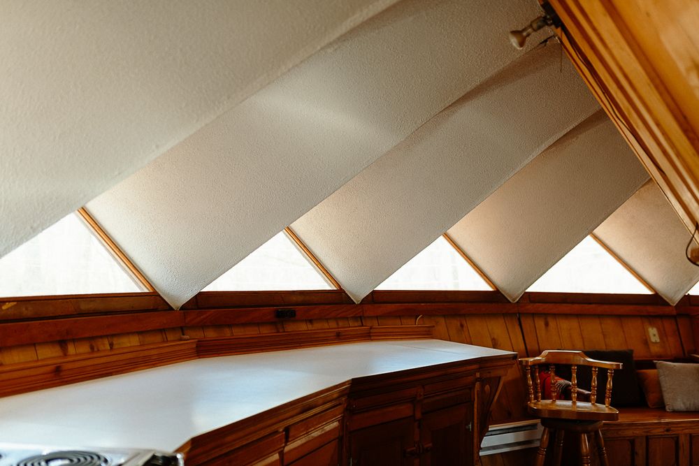 Wooden interior of a boat cabin with angled white panels and skylights creating a geometric ceiling design.