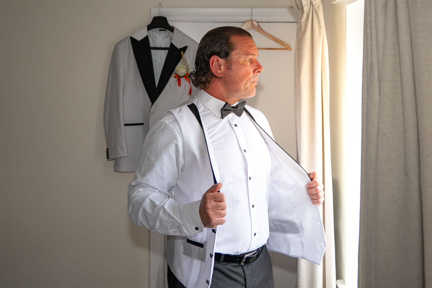 Groom in white tuxedo shirt with bow tie preparing to dress for a formal wedding day.Yorkshire, Sheffield, Lincolnshire, UK