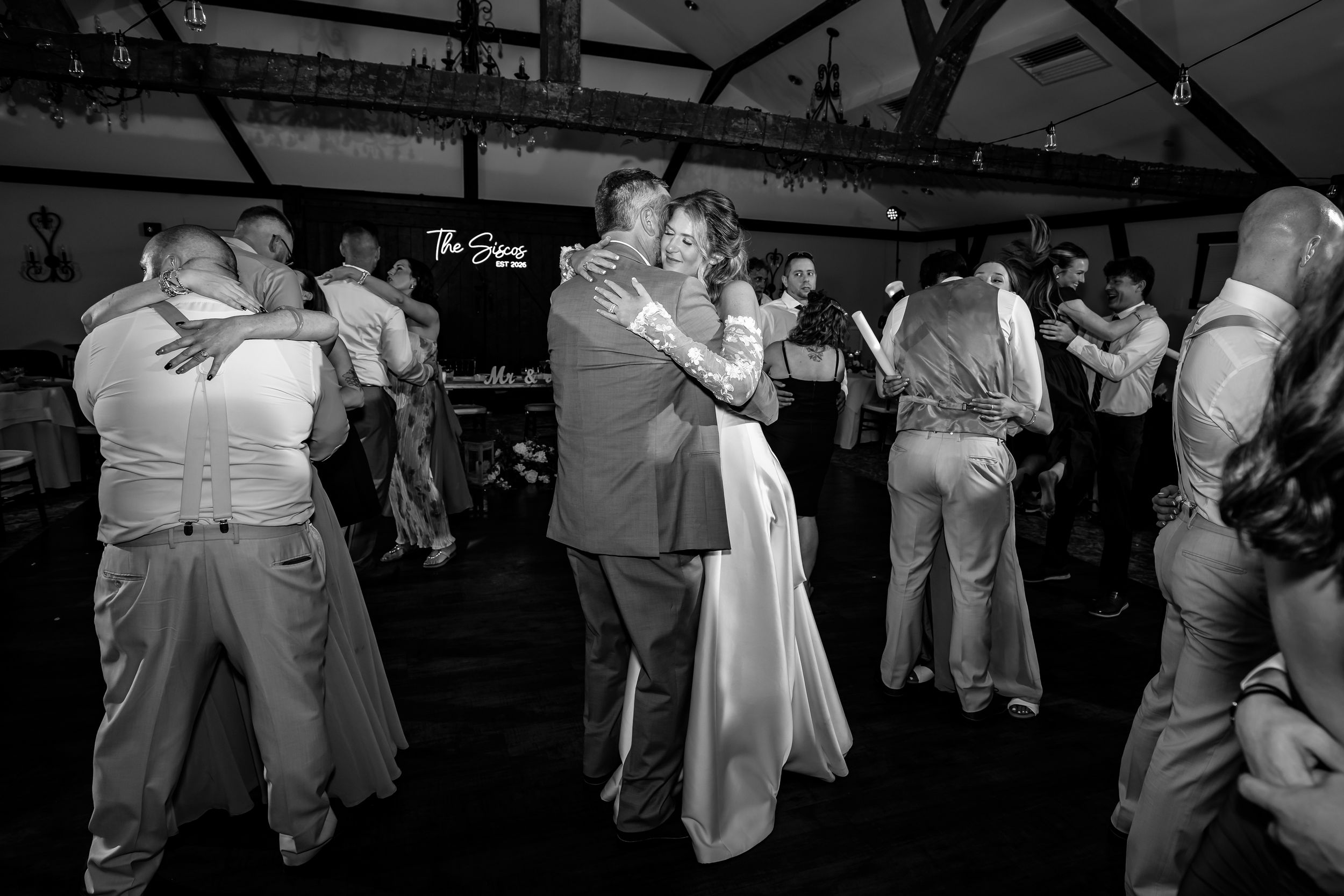 Bride and groom share first dance surrounded by guests at wedding reception.