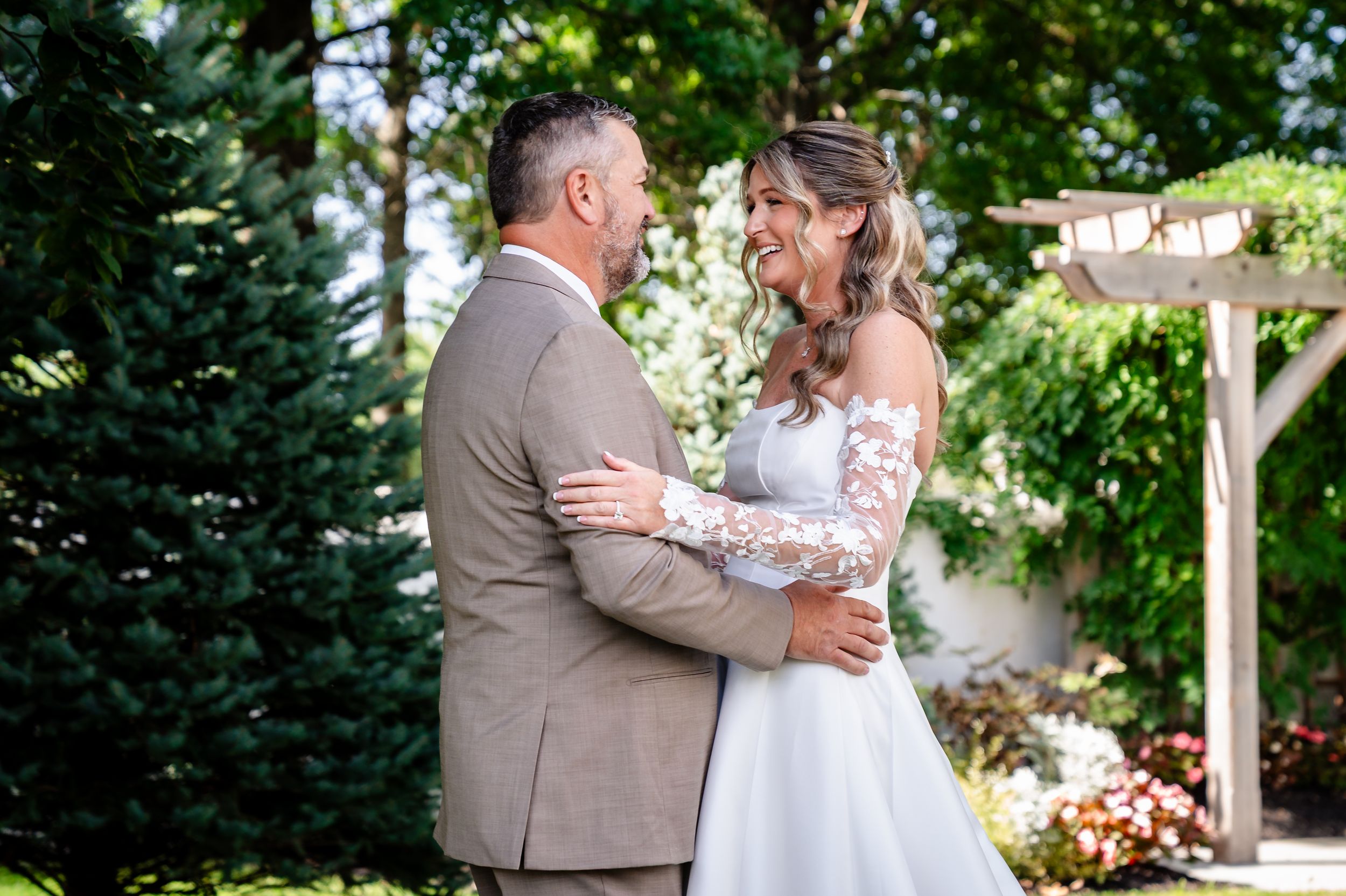 Bride and groom share tender first look moment in lush garden setting.