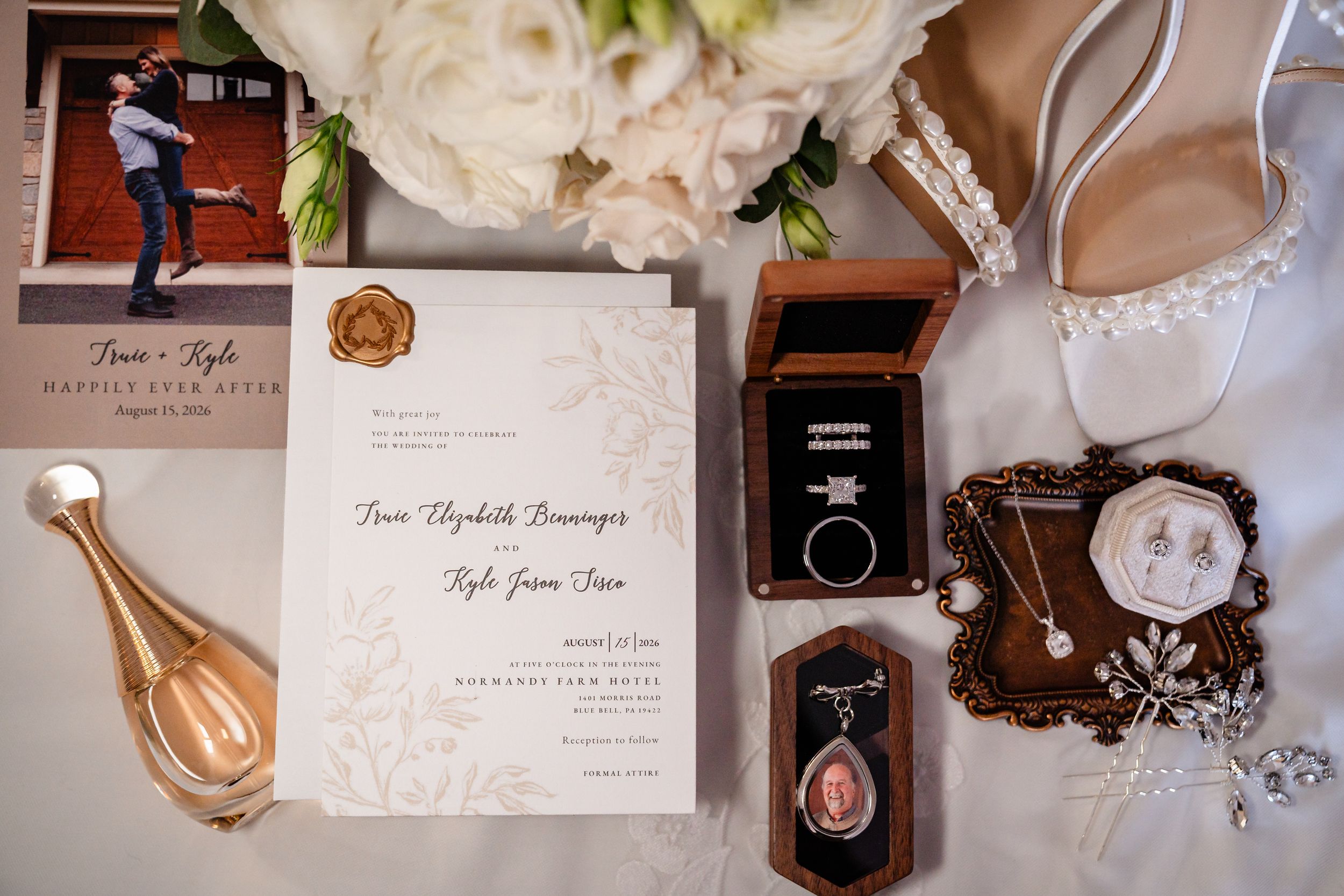 Elegant wedding flat lay featuring invitations, rings, jewelry, and bridal accessories on a neutral background.
