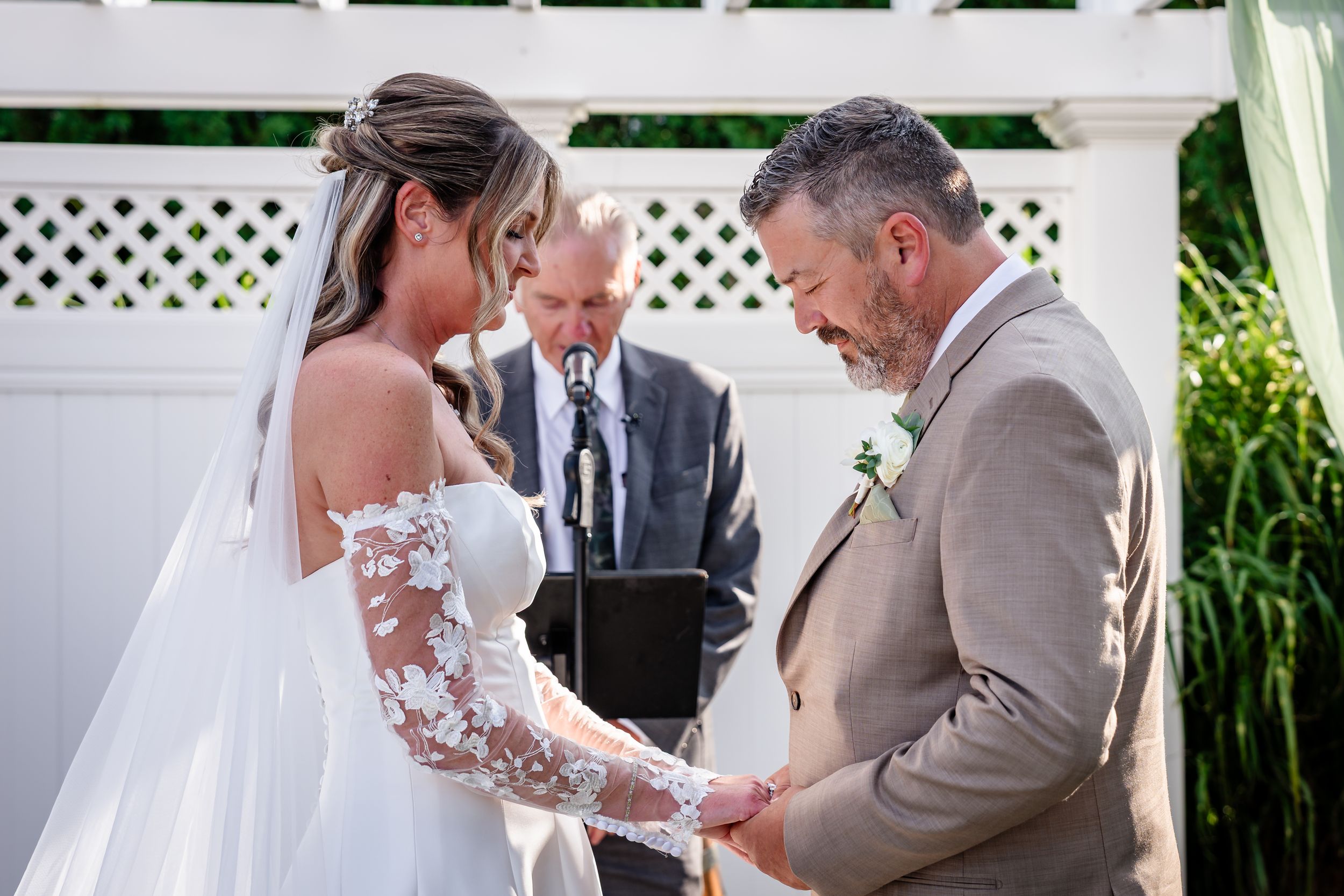 Bride and groom holding hands during outdoor wedding ceremony.