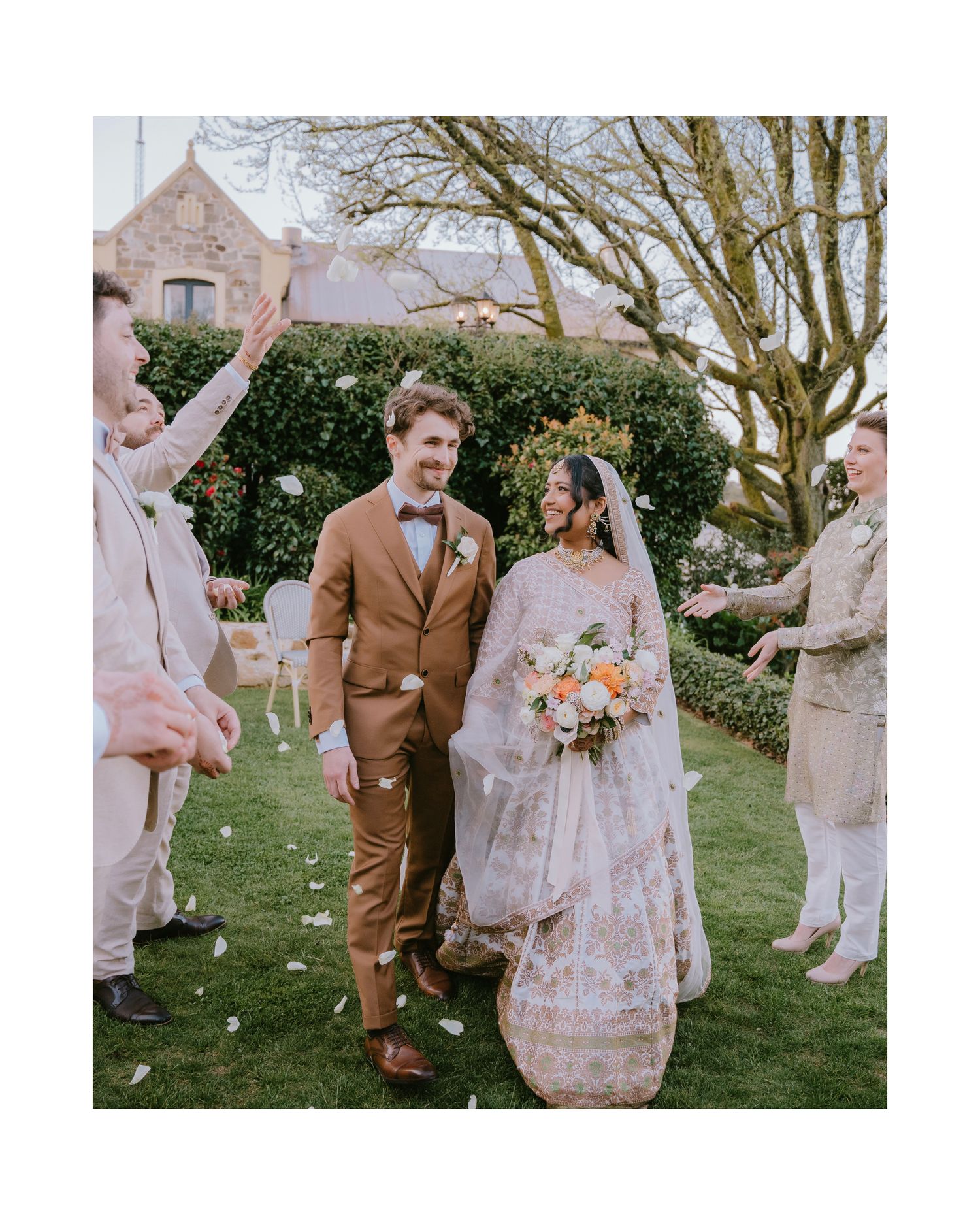 Guests toss petals as the newlyweds walk across the lawn - Adelaide wedding ceremony exit photography