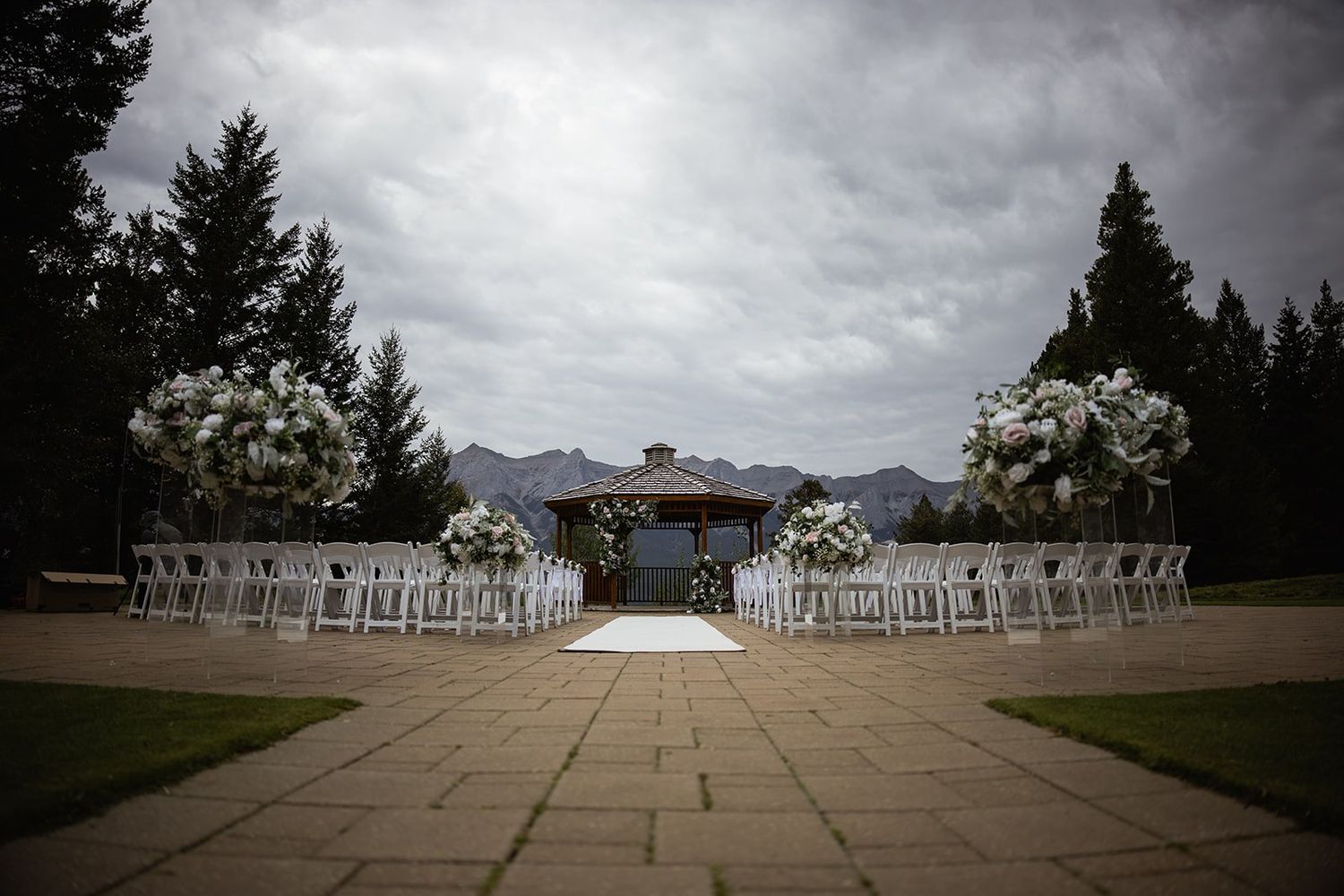 Empty ceremony setup at the Gazebo at Silvertip Resort with white florals and mountains