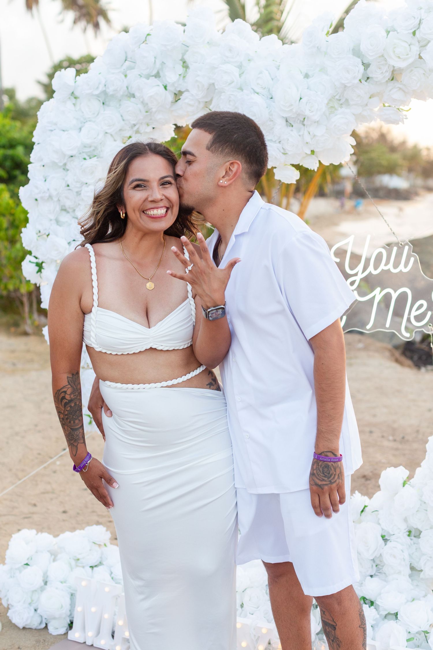 Marriage proposal. Man, woman, and decorative setup with white flower heart overlooking the ocean in Río Grande, Puerto Rico.