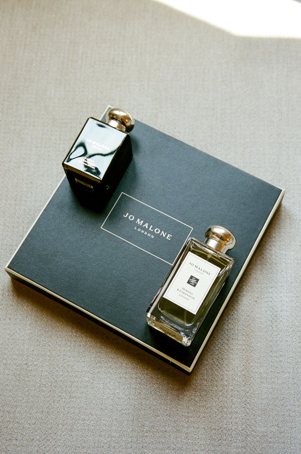 Jo Malone London perfume bottle and black fragrance box displayed on a dark gift box packaging.