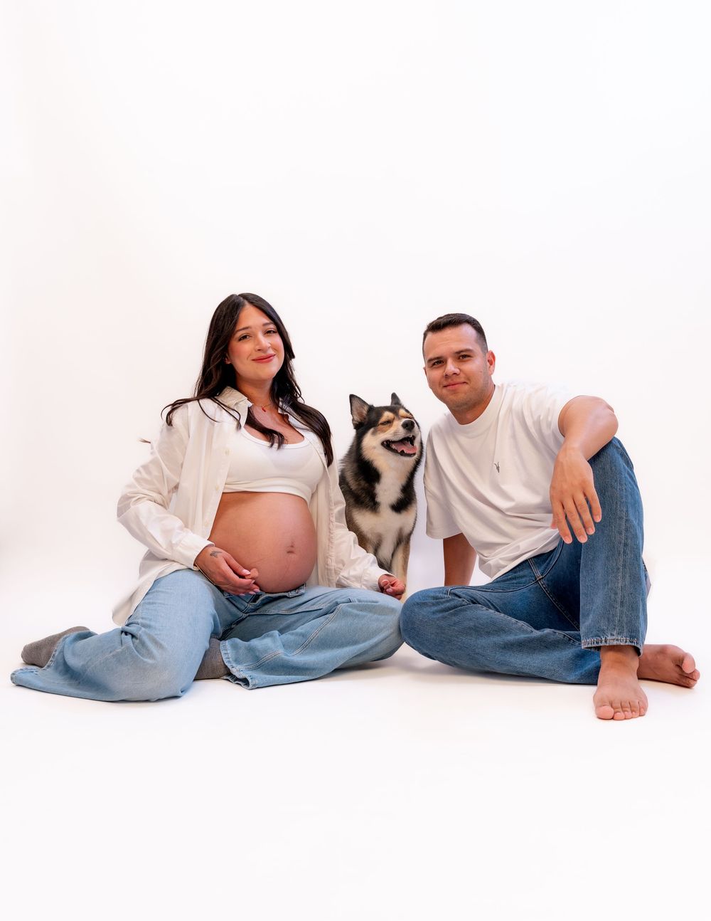 Studio maternity portrait of an expecting couple with their dog, celebrating family, love, and the anticipation of a new arrival.
