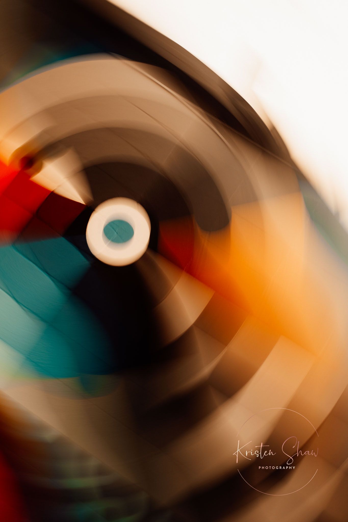Abstract motion blur photo of a spinning vinyl record with colorful teal, red, and orange light streaks.