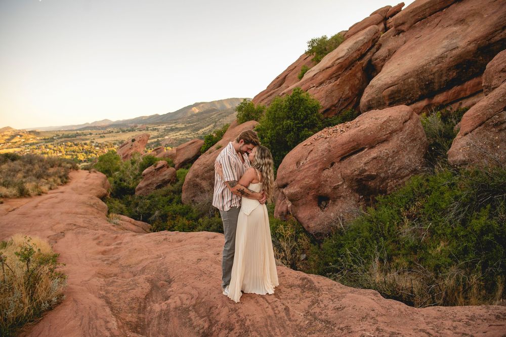 Couple embracing among red rock formations at Red Rocks Park, Colorado, during golden hour sunset.
