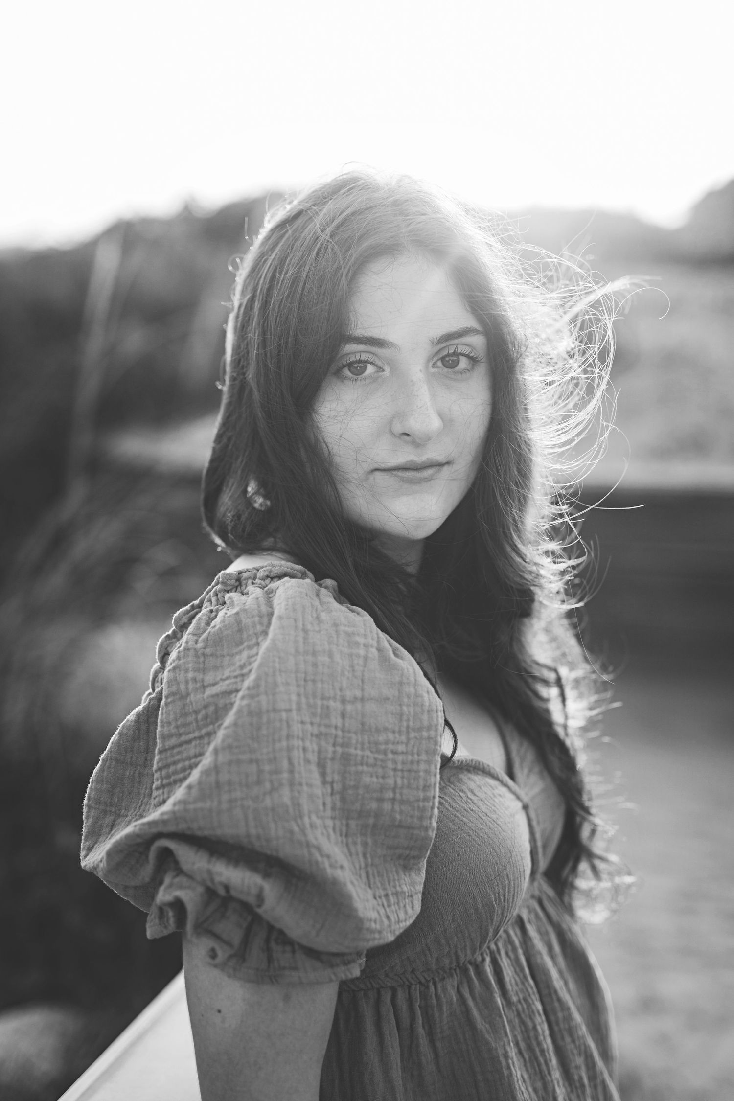 Dramatic black and white portrait with figure in puff-sleeve dress against natural lighting.