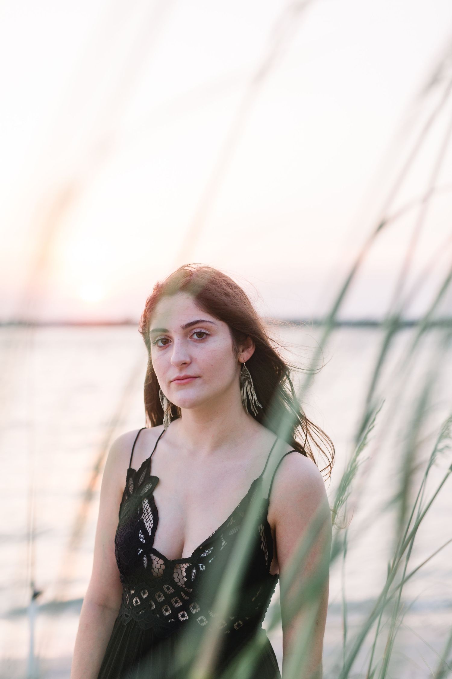 Dreamy sunset portrait through sea grass near the water.