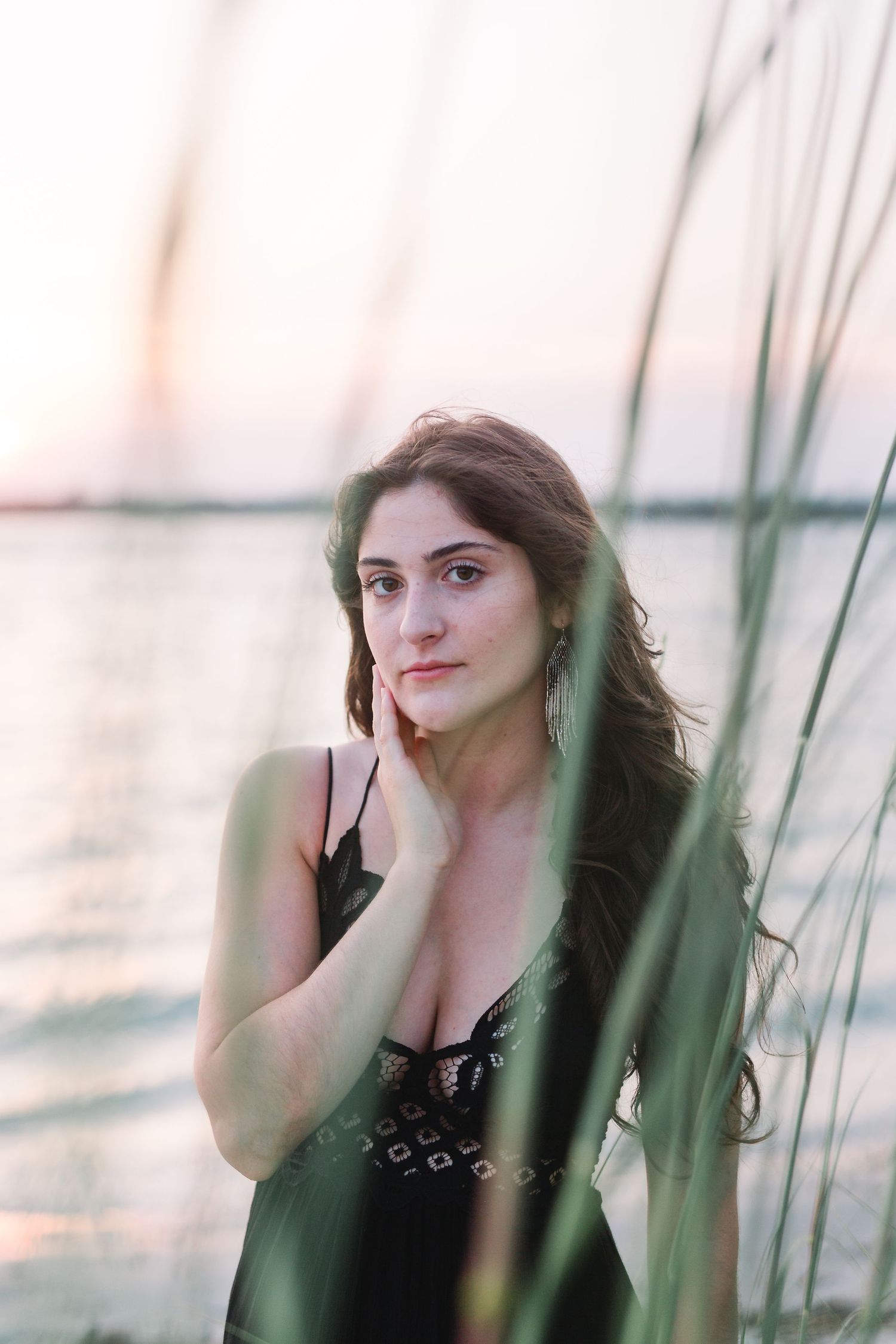 Soft portrait through seaside grasses at golden hour.