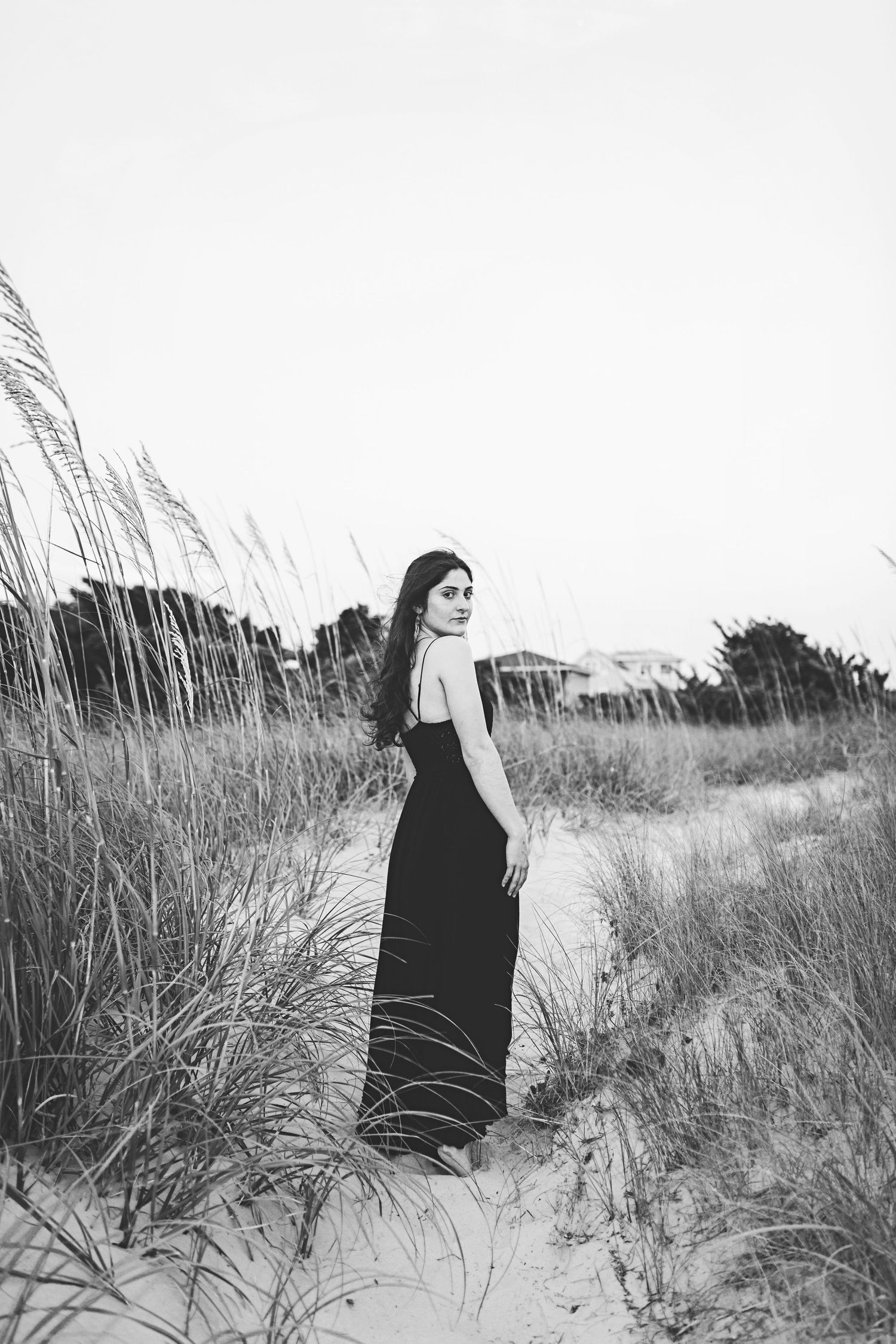 Black and white portrait of someone in a maxi dress among beach grass.