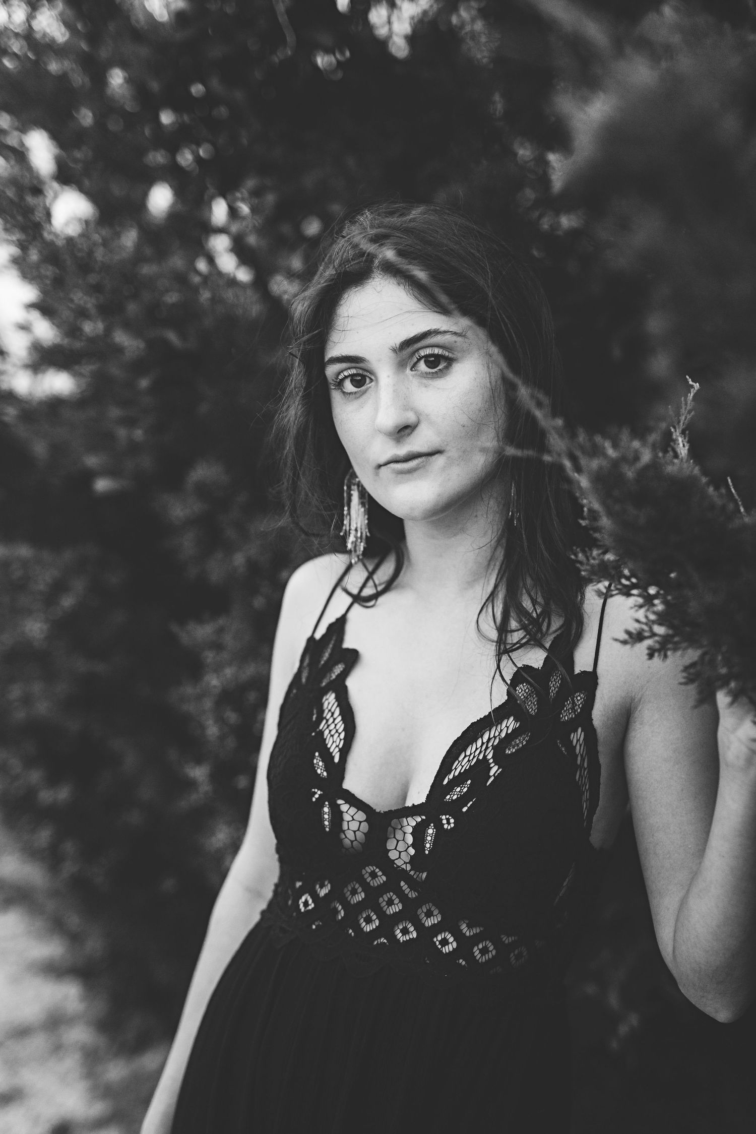 Dramatic black and white portrait surrounded by bokeh foliage.