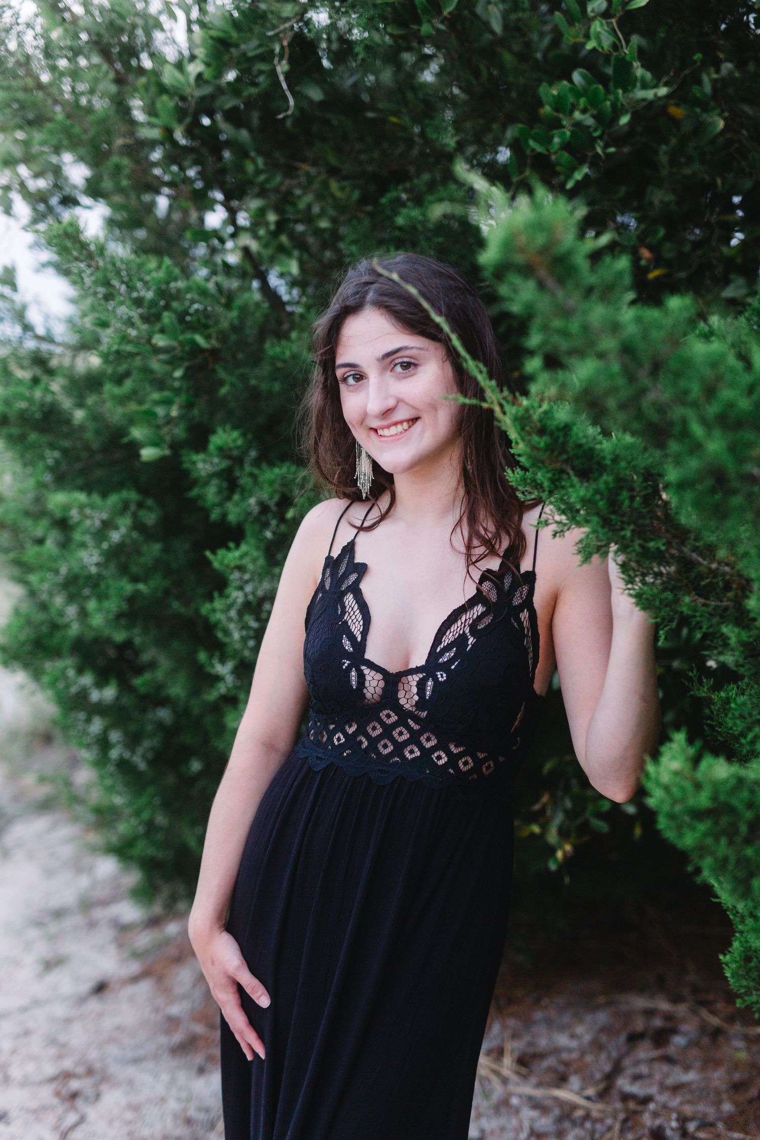 A fashion portrait featuring a black lace dress against a natural green backdrop.