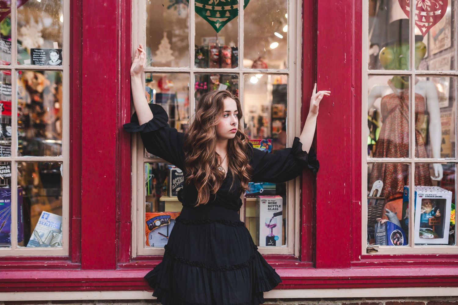 Fashion portrait against red storefront windows with festive holiday decorations.