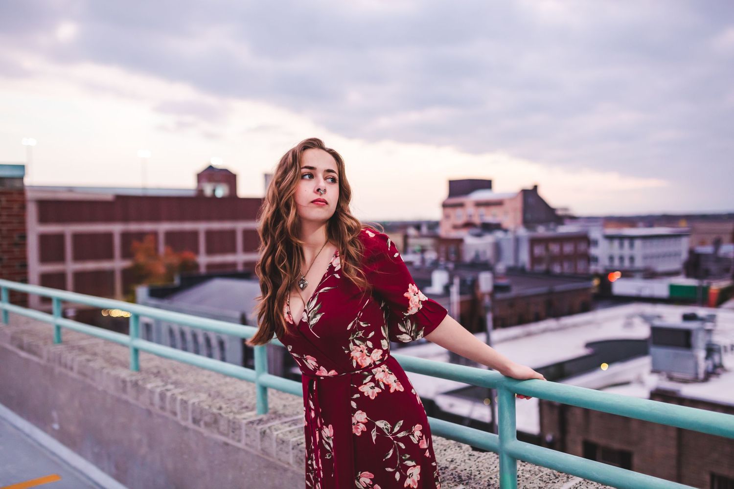 A flowing burgundy floral dress captured against an urban rooftop setting during sunset.