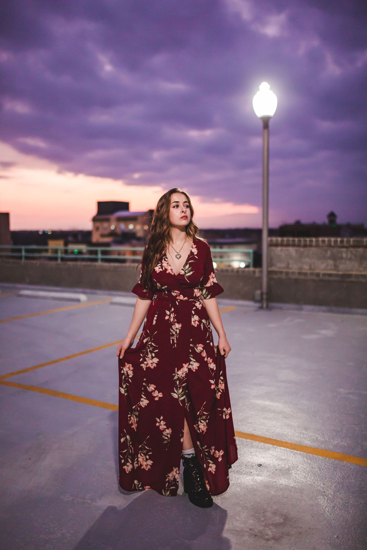 Fashion shoot at sunset featuring burgundy floral dress and dramatic purple sky.
