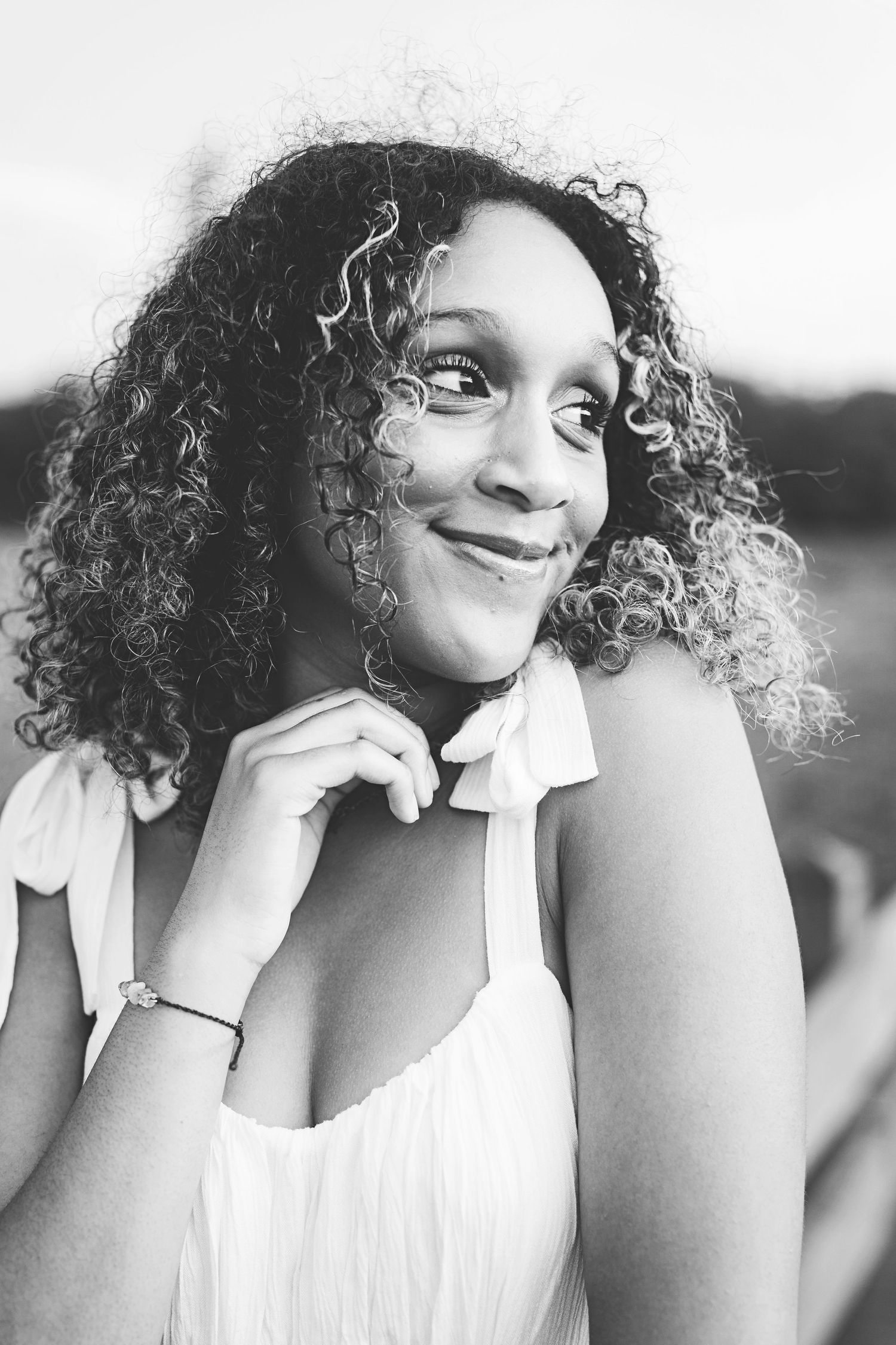 A close-up black and white portrait showing a joyful expression and natural curly hair.