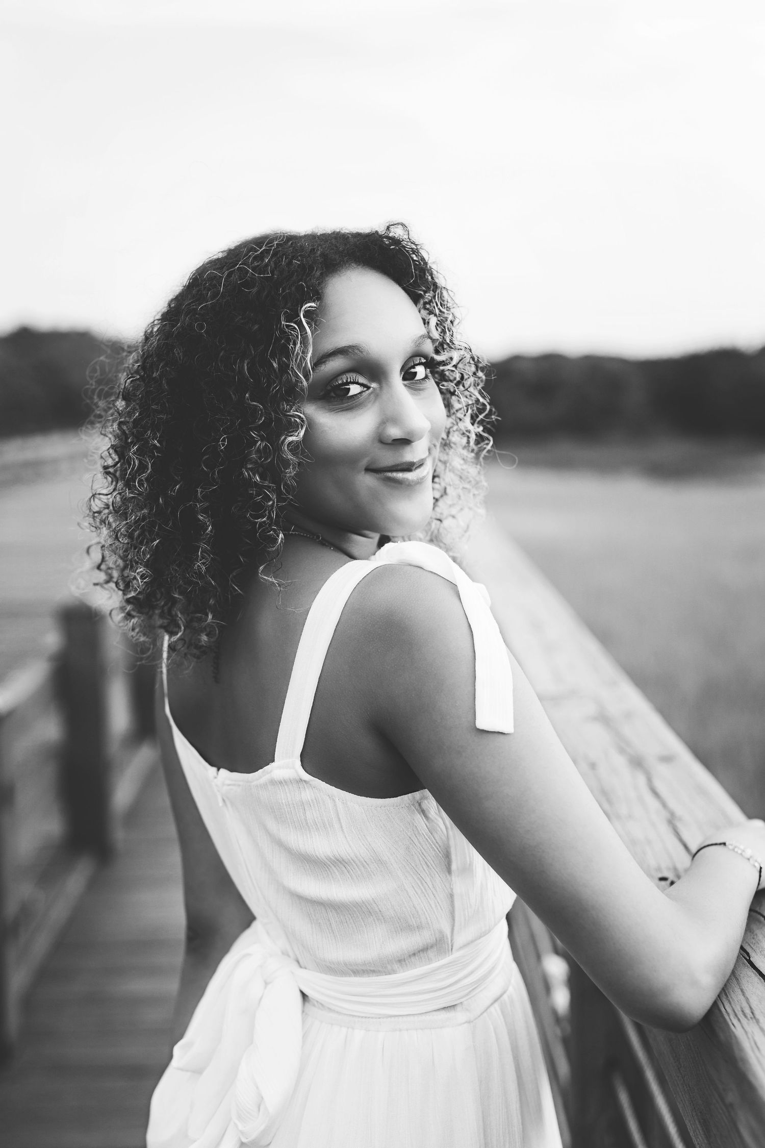 Black and white portrait on wooden boardwalk with white summer dress.