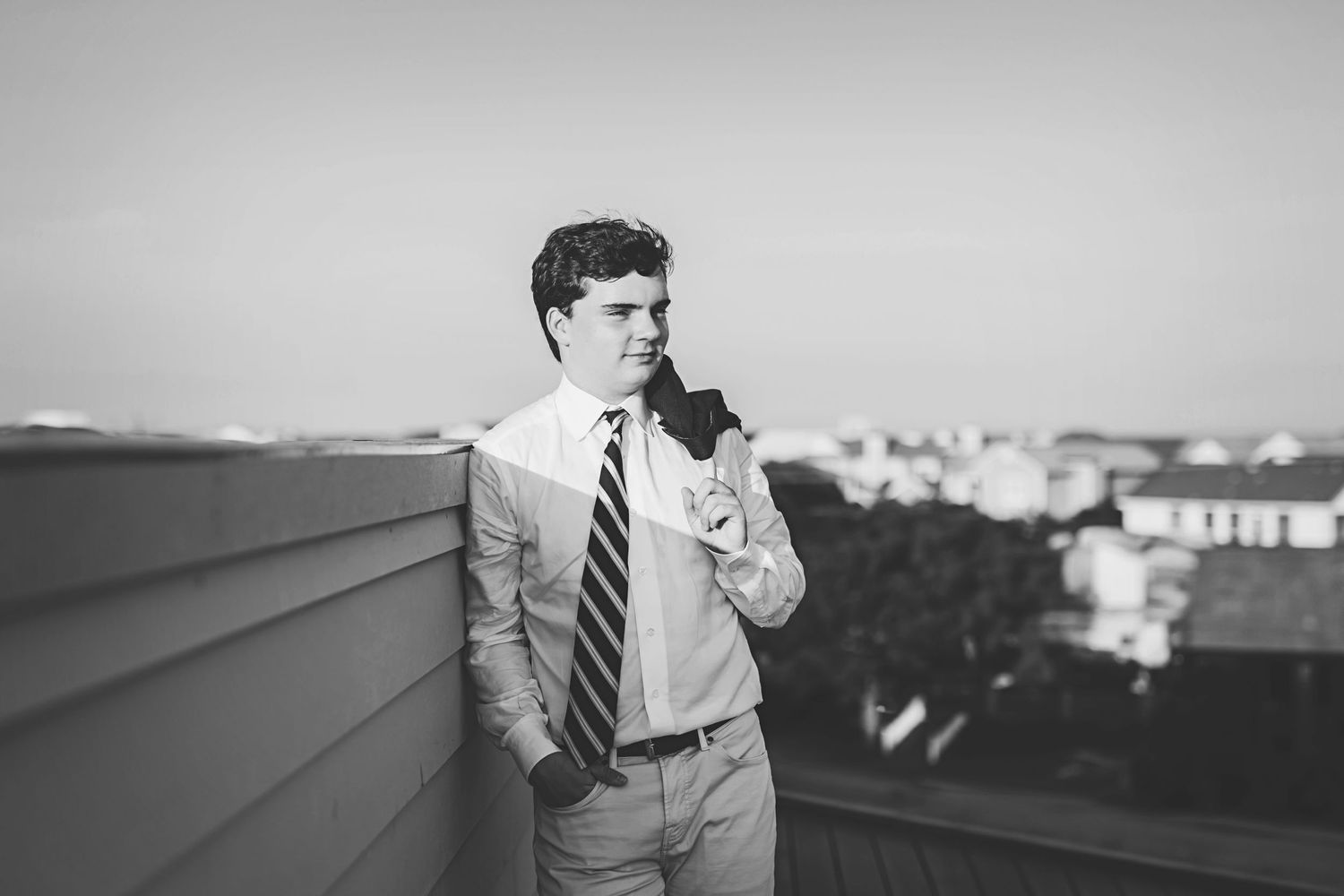Black and white rooftop portrait of someone in business attire against an urban backdrop.