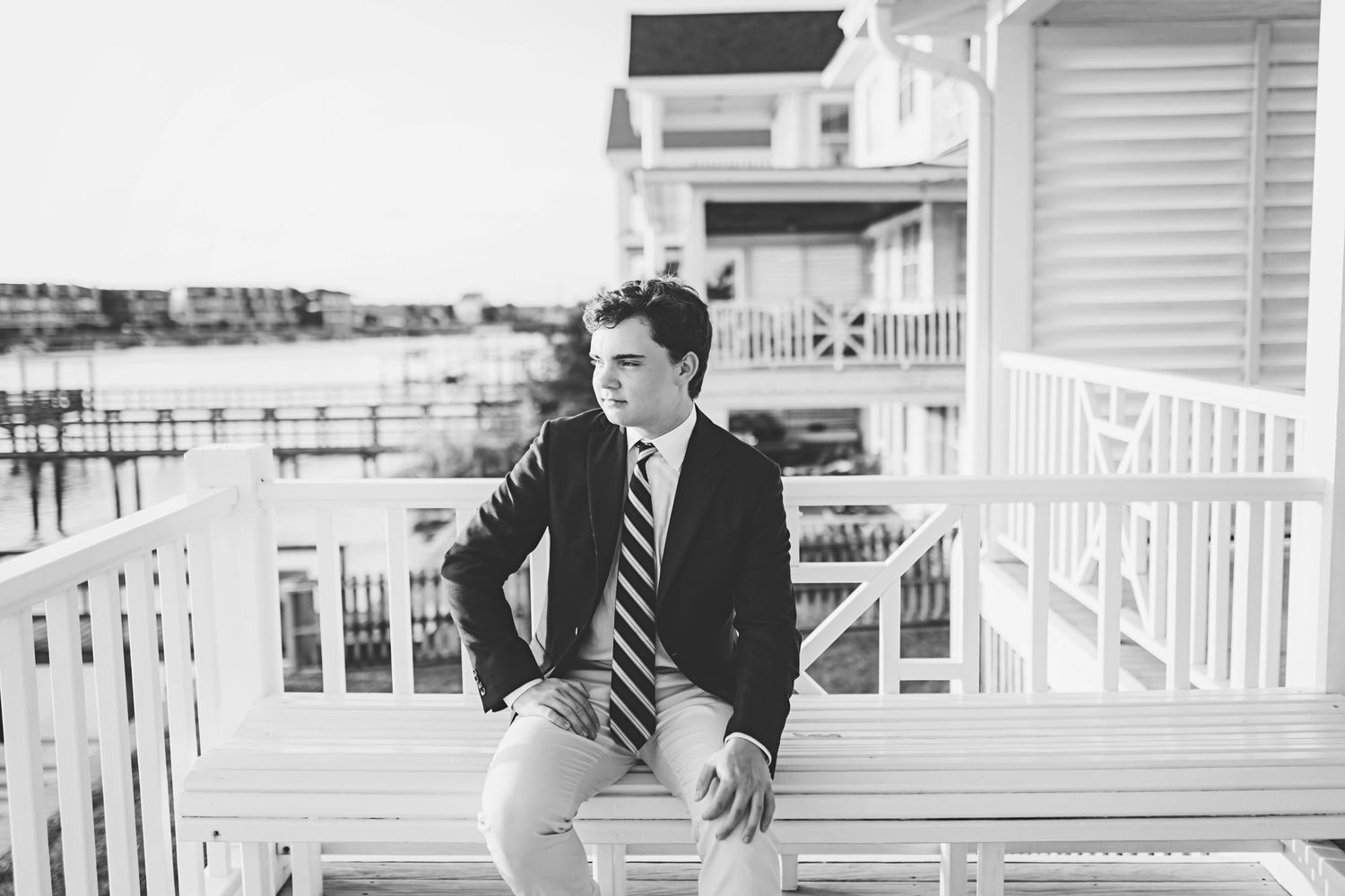 Black and white photo of someone in formal wear on a coastal home's white balcony.