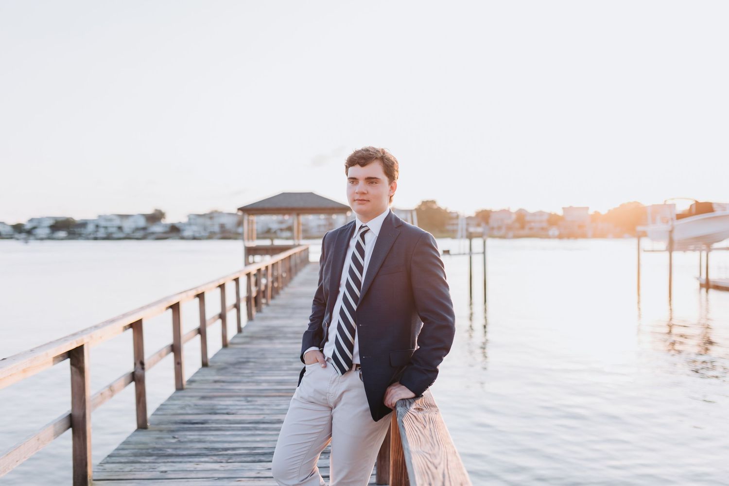 Casual professional pose on wooden pier with water view.