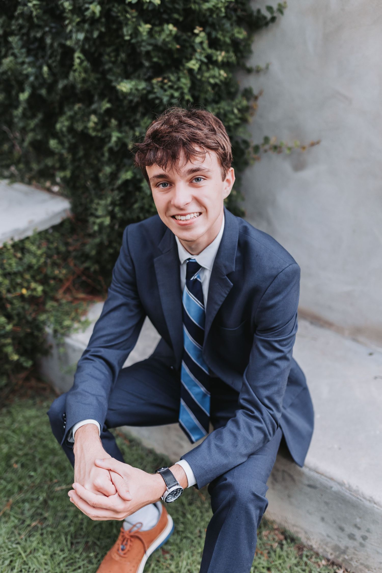 Cheerful outdoor portrait showing professional attire and casual seated pose.